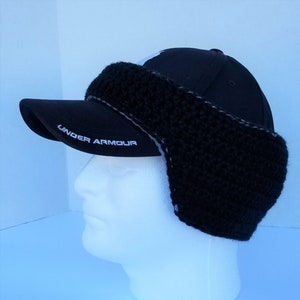 May include: Black baseball cap with a black crocheted ear warmer attached. The cap has the words "Under Armour" embroidered on the brim.