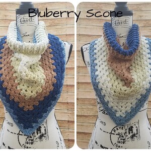May include: A crocheted infinity scarf in shades of blue, brown, and white. The scarf is displayed on a mannequin and has a textured, granny square pattern.