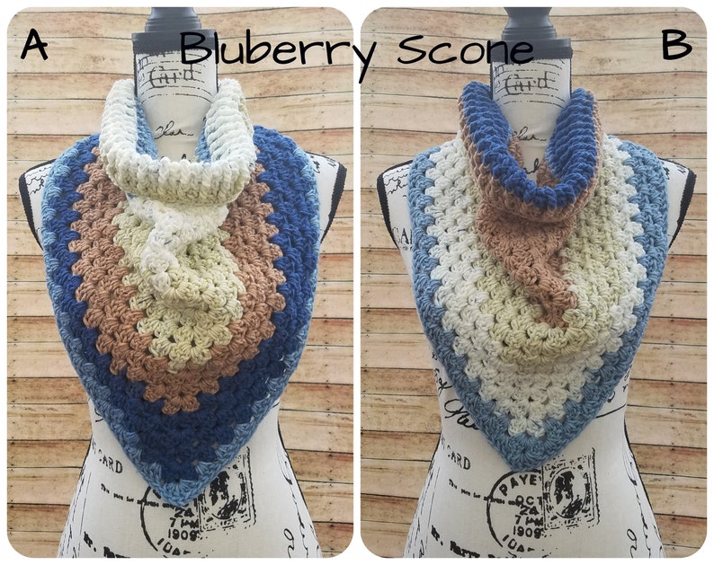 May include: A crocheted infinity scarf in shades of blue, brown, and white. The scarf is displayed on a mannequin and has a textured, granny square pattern.