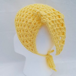 May include: A yellow crocheted hat with a tie at the back. The hat is made with a simple stitch pattern and has a loose, airy feel.