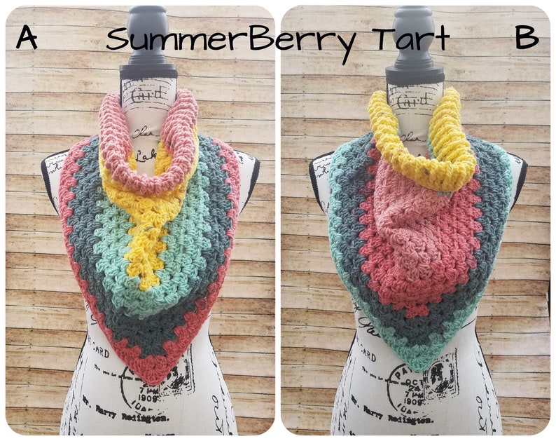 May include: Two crocheted infinity scarves, one in shades of teal, yellow, and pink, and the other in shades of pink, teal, and gray. The scarves are displayed on a white mannequin with a wooden base. The text "Summer Berry Tart" is written above the scarves.
