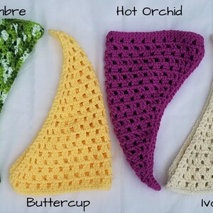 May include: Four crocheted triangle scarves in different colors: lime ombre, buttercup yellow, hot orchid, and ivory.