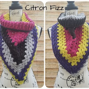 May include: Two crocheted cowl neck scarves in a triangular shape. The scarf on the left is grey, purple, black, yellow, and pink. The scarf on the right is grey, purple, yellow, pink, and black. The scarves are labeled "A" and "B" and "Citron Fizz".