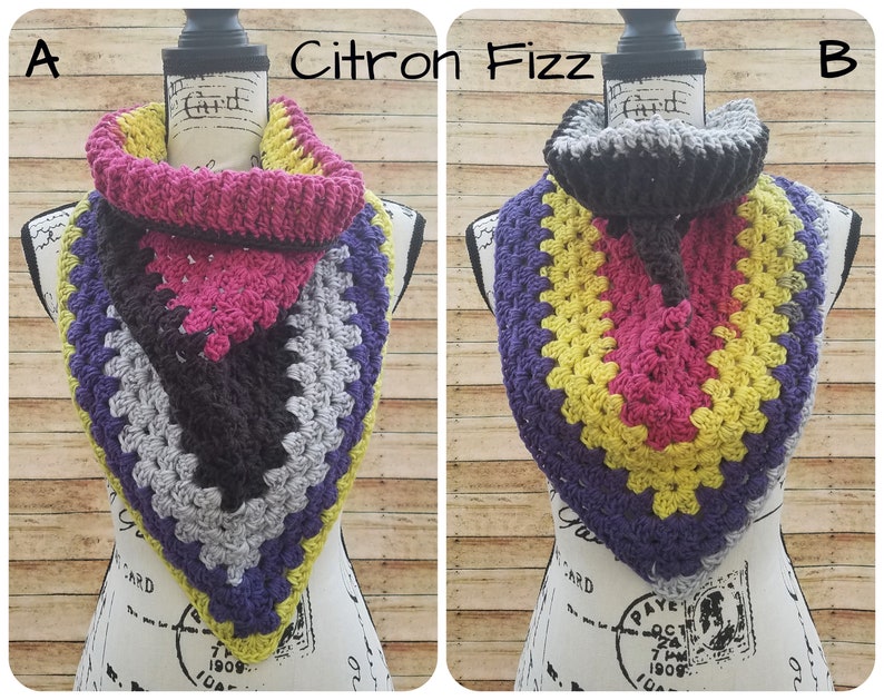 May include: Two crocheted cowl neck scarves in a triangular shape. The scarf on the left is grey, purple, black, yellow, and pink. The scarf on the right is grey, purple, yellow, pink, and black. The scarves are labeled "A" and "B" and "Citron Fizz".