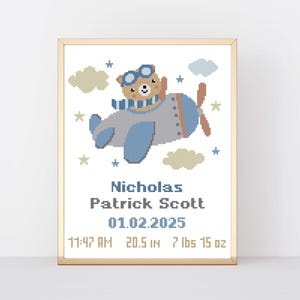 Peut inclure: Une œuvre d'art au point de croix encadrée représentant un ours dans un biplan, avec des nuages et des étoiles. Le texte indique "Nicholas Patrick Scott 01.02.2025 11:47 AM 52.1 cm 3.4 kg 425 g". L'œuvre est dans des tons de bleu, beige et marron.