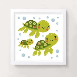 May include: A cross-stitch pattern featuring three green turtles with smiling faces and colourful shells. The turtles are swimming in a white background with blue bubbles.