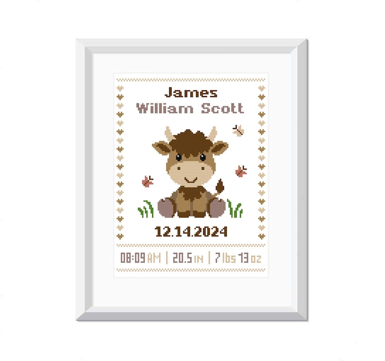 Pu&ograve; includere: Un ricamo a punto croce incorniciato in bianco con un toro di cartone animato marrone e bianco con il testo "James William Scott", "12.14.2024", "08:09 AM", "20.5 IN", "7 lbs 13 oz" in testo marrone.