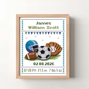 May include: A framed cross-stitch artwork featuring sports equipment: a football, soccer ball, baseball glove, and a blue helmet. The text reads "James William Scott" with the date, time, height (21.5 in), and weight (7 lbs 5 oz).
