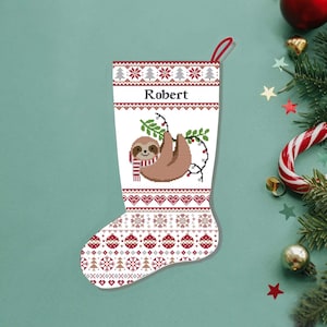 May include: A Christmas stocking with a sloth design. The white stocking features a brown sloth hanging from a branch with lights. The name "Robert" is printed above the sloth. The stocking has a red loop for hanging and a patterned design.