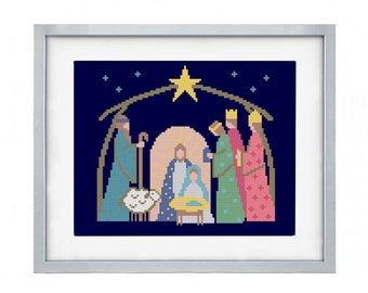 May include: A framed cross-stitch artwork depicting the nativity scene with Mary, Joseph, and baby Jesus in a manger. Three wise men stand behind them, and a star shines above. The background is a dark blue with white stars.