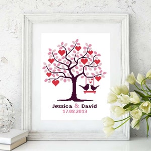 May include: A white frame with a white background containing a pink and red heart tree with two black birds on a swing. The text below the tree reads "Jessica & David 17.08.2019".