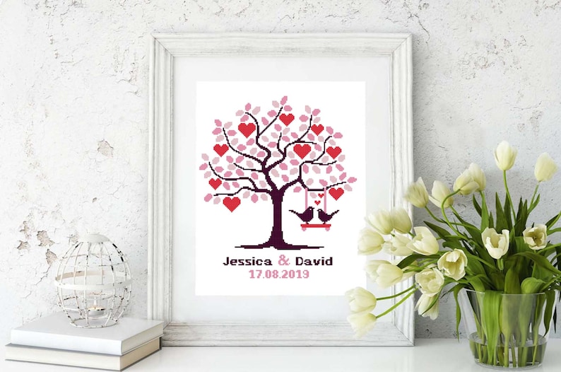 May include: A white frame with a white background containing a pink and red heart tree with two black birds on a swing. The text below the tree reads "Jessica & David 17.08.2019".