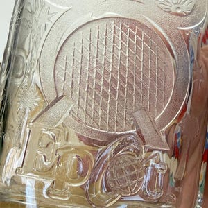 以下が含まれることがあります： 「Epcot」の文字と地球儀がエンボス加工された透明なガラスタンブラー。ミッキーマウスの頭やその他の装飾要素も付いています。「Disney World」の文字が下部にあります。