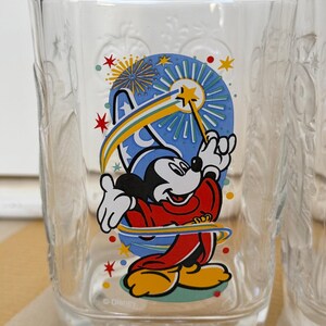 以下が含まれることがあります： ミッキーマウスが魔法使いの衣装を着て、星の杖を持っているカラフルなグラフィックが特徴の透明なガラス。 デザインには花火と2000年が含まれています。 ガラスには装飾的なエンボス加工が施されています。