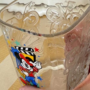 以下が含まれることがあります： カラフルなミッキーマウスのグラフィックが入った、透明なガラス製の正方形のグラス。グラスには、星と幾何学模様がエンボス加工されています。ミッキーマウスのグラフィックには、映画のクローザーと赤い星が含まれています。