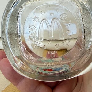 以下が含まれることがあります： マクドナルドのロゴと「フランス」と「20」の文字がガラスにエッチングされた、透明なガラス製のマクドナルドのグラスベース。ガラスには星やその他の形をした円形のデザインが施されています。