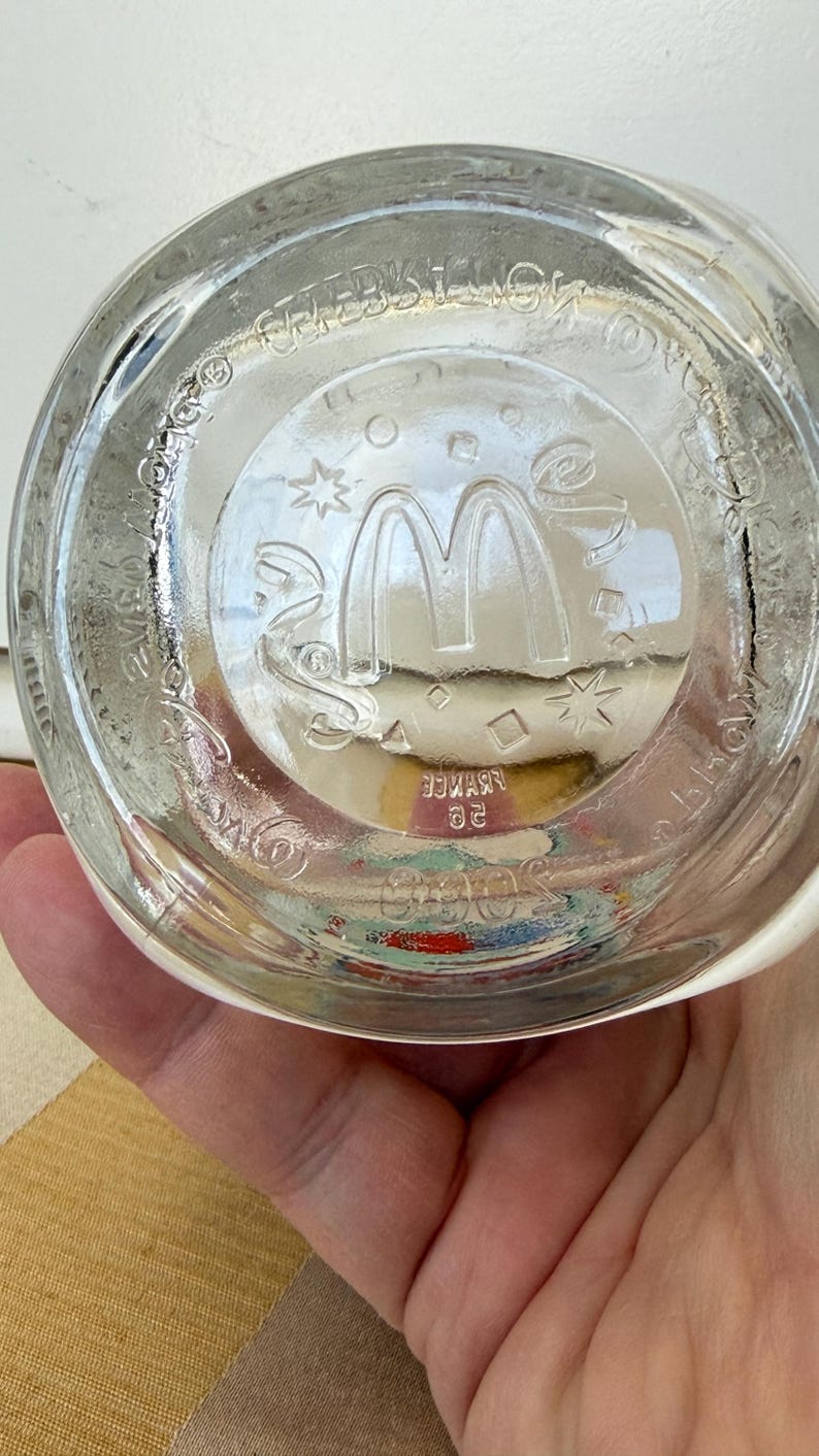 以下が含まれることがあります： マクドナルドのロゴと「フランス」と「20」の文字がガラスにエッチングされた、透明なガラス製のマクドナルドのグラスベース。ガラスには星やその他の形をした円形のデザインが施されています。