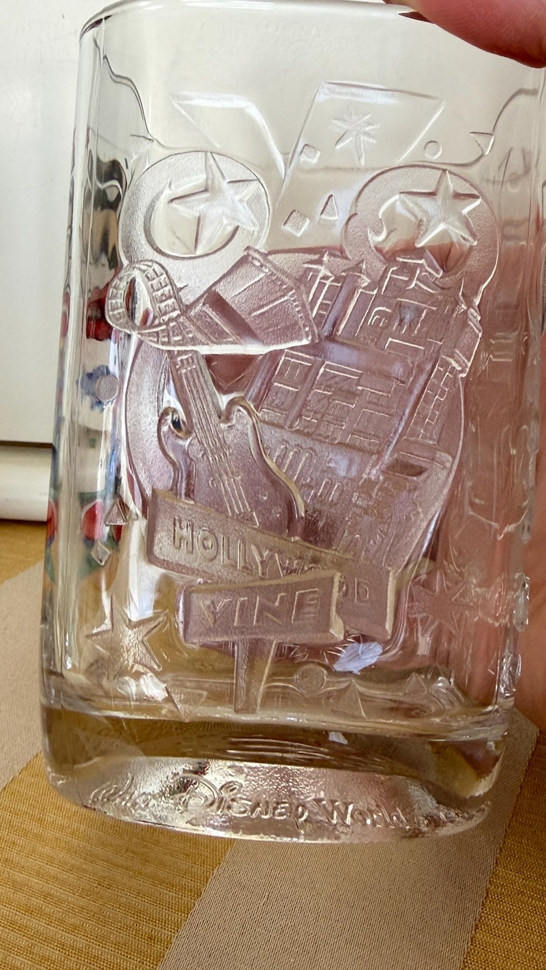 以下が含まれることがあります： ハリウッド・ヴァインのデザインがエンボス加工された透明なガラスタンブラー。ギター、星、建築要素が特徴です。グラスの底には「ディズニーワールド」と刻印されています。