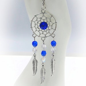 May include: Silver dreamcatcher with a blue crystal in the center and blue and clear crystal beads hanging from it. Three silver feathers hang from the bottom of the beads.