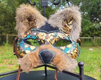May include: A masquerade mask with gold and turquoise scales, brown fur accents, and a brown leather cord with beads.