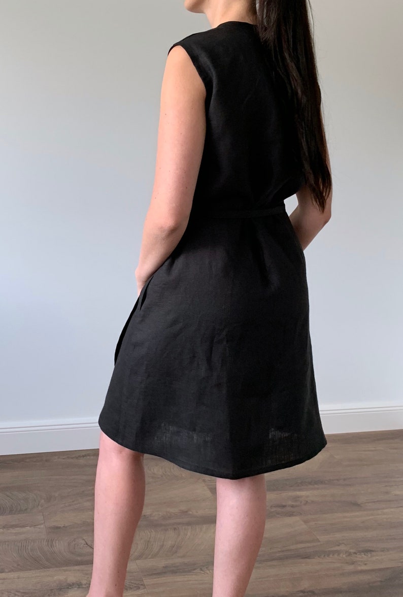 May include: A black sleeveless linen dress with a tie belt. The dress is knee-length and has a relaxed fit.