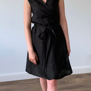 May include: A black linen wrap dress with a V-neckline and a tie belt.