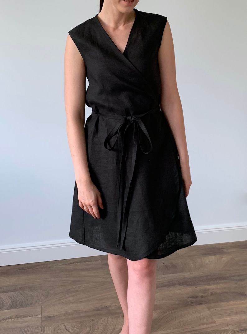 May include: A black linen wrap dress with a V-neckline and a tie belt.