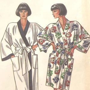 May include: New Look 6312 sewing pattern envelope featuring illustrations of two robe styles. One robe is solid white with dark trim, and the other is white with a multi-coloured floral print. Both robes feature wide sleeves, tie waists, and pockets.