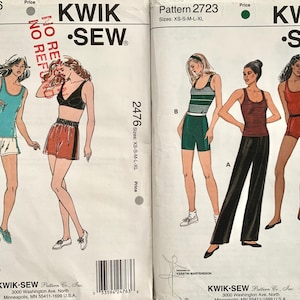 May include: Two vintage Kwik Sew sewing patterns. Pattern 2476 shows illustrations of athletic wear, including a teal vest and shorts, and a black bra and red shorts. Pattern 2723 features a striped top and shorts, a striped vest and black trousers, and a red vest and shorts.