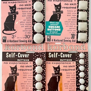 May include: Vintage Korbond self-cover button cards. Each card features a black cat illustration and text. The cards display round and square white buttons. The cards are pink and black.