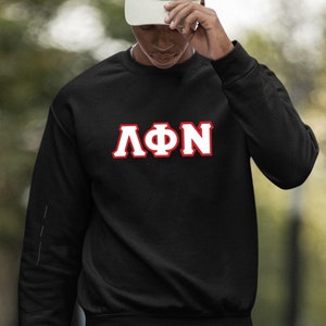 Könnte beinhalten: Schwarzes Sweatshirt mit rotem und weißem Appliké der Buchstaben "ΛΦΝ" mit Zickzack-Stich. Das Sweatshirt wird von einer Person getragen, die eine weiße Baseballkappe und schwarze Shorts trägt.