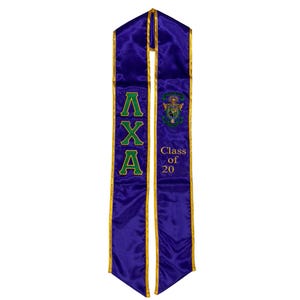 May include: A purple graduation sash with gold trim. The sash features the Greek letters ΛXA in green, along with a crest and the text "Class of 20". The sash is made of a shiny, satin-like material.