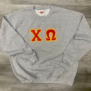 May include: A gray sweatshirt with a red and yellow embroidered "ΧΩ" on the front.