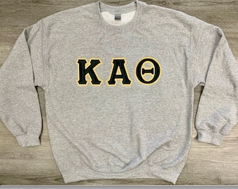 May include: A gray sweatshirt with the letters "KAΘ" in black with a gold outline.