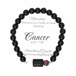 May include: Black beaded bracelet with a silver charm that says "Cancer" and a red gemstone. The bracelet is labeled "Moonstone, Passionate Love, Fertility & Lucid Dreaming" and "Strawberry Quartz, ing & Overcoming Mental Ans".