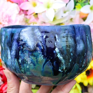 May include: A blue and green ceramic bowl with a textured, uneven surface. The bowl has a glossy finish and is decorated with white and blue swirls.