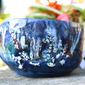 May include: A blue ceramic bowl with white and red abstract patterns. The bowl has a glossy finish and is decorated with white and red swirls.