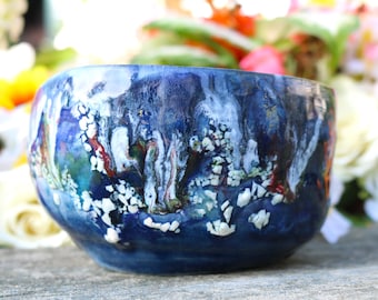 May include: A blue ceramic bowl with white and red abstract patterns. The bowl has a glossy finish and is decorated with white and red swirls.