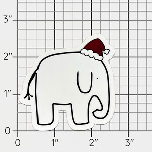 以下が含まれることがあります： 白い象が赤いサンタの帽子をかぶっています。帽子には白い縁取りがあります。象は4本足で立っており、小さな尻尾があります。