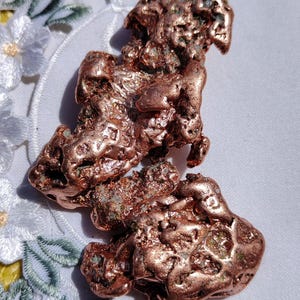 May include: A large, rough piece of copper ore with a reddish-brown color and a green patina. The ore is irregularly shaped and has a textured surface.