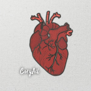 Puede incluir: Parche bordado con un detallado corazón anatómico en tonos rojos y grises. El diseño incluye intrincadas venas y arterias, sobre un fondo blanco texturizado. El texto "CozyAit" está en la esquina inferior izquierda.