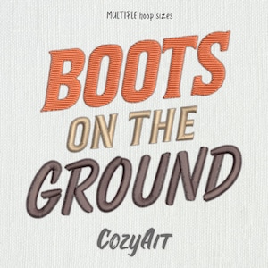 May include: Embroidered design on a white fabric background. The design reads "BOOTS ON THE GROUND" in a stylized font. The word "BOOTS" is in orange, "ON THE" is in beige, and "GROUND" is in gray. The text "CozyAit" is in gray at the bottom of the design.