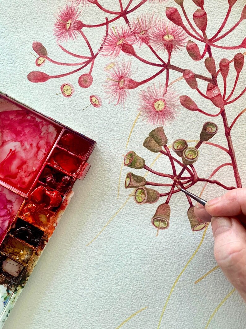 May include: A watercolour painting of a pink flower with green buds. The artist is using a small brush to paint the buds. A watercolour palette with red, orange, and yellow paint is in the bottom left corner of the image.