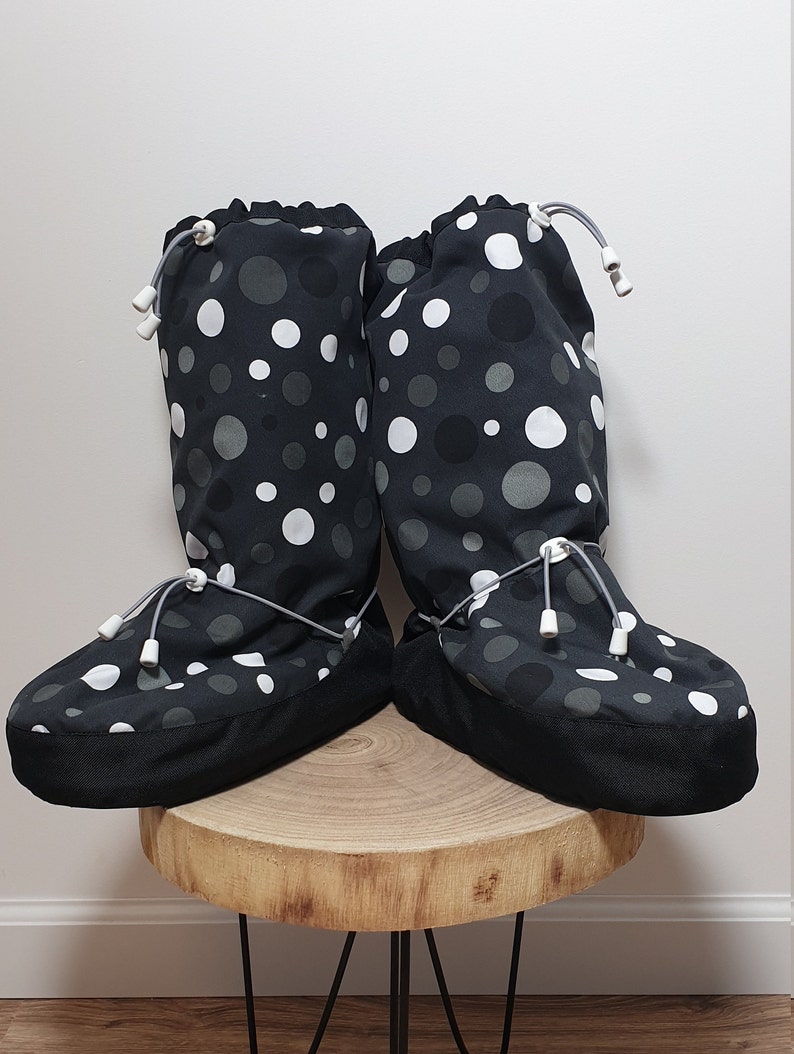 May include: A pair of black and white polka dot boot covers with a drawstring closure. The boot covers are made of a soft, comfortable fabric and are perfect for keeping your feet warm and dry.