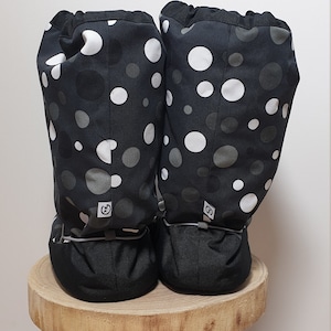 May include: A pair of black fabric boot covers with a white and gray polka dot pattern. The boot covers have a drawstring at the top and a black elastic band at the bottom.