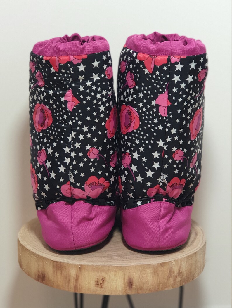 May include: A pair of pink and black fleece boot covers with a floral and star pattern. The boot covers are made of a soft, comfortable material and are perfect for keeping your feet warm in the winter.