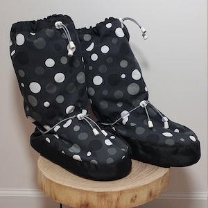 May include: A pair of black and white polka dot boot covers with a drawstring closure. The boot covers are made of a soft, water-resistant material and are perfect for keeping your feet warm and dry in cold weather.