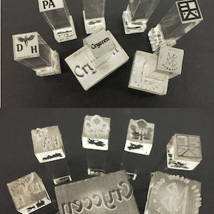 以下が含まれることがあります： 様々なデザインとテキストが施された、透明なアクリルスタンプのコレクション。イニシャル、ロゴ、または「Cryccen」のテキストが表示されているスタンプもあります。スタンプは長方形で、透明なハンドルが付いています。