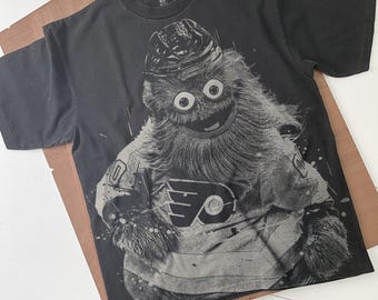 Gritty Bleached T-Shirt: Vintage Ice Hockey Mascot Faded Black Cotton Unisex Tee