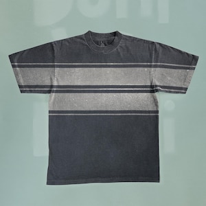 Peut inclure: Un t-shirt noir à rayures blanches délavées. Le t-shirt a un col rond et des manches courtes.